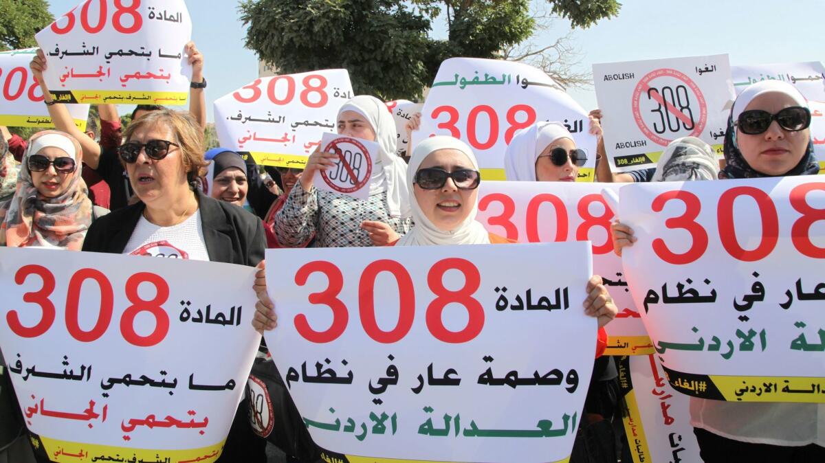 Protesters in front of Jordan's parliament in Amman hold banners calling for the repeal of a provision that allows a rapist to escape punishment if he marries his victim.