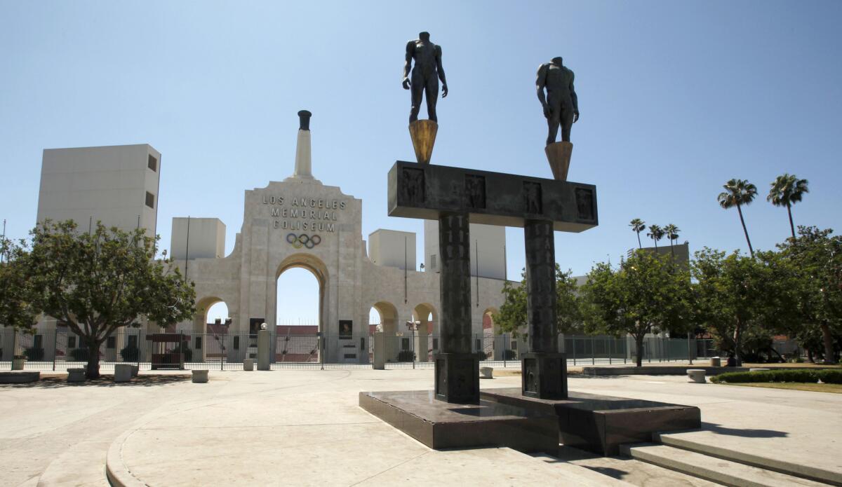 The Los Angeles Memorial Coliseum with a pair of athlete statues installed for the 1984 Summer Olympics, foreground.