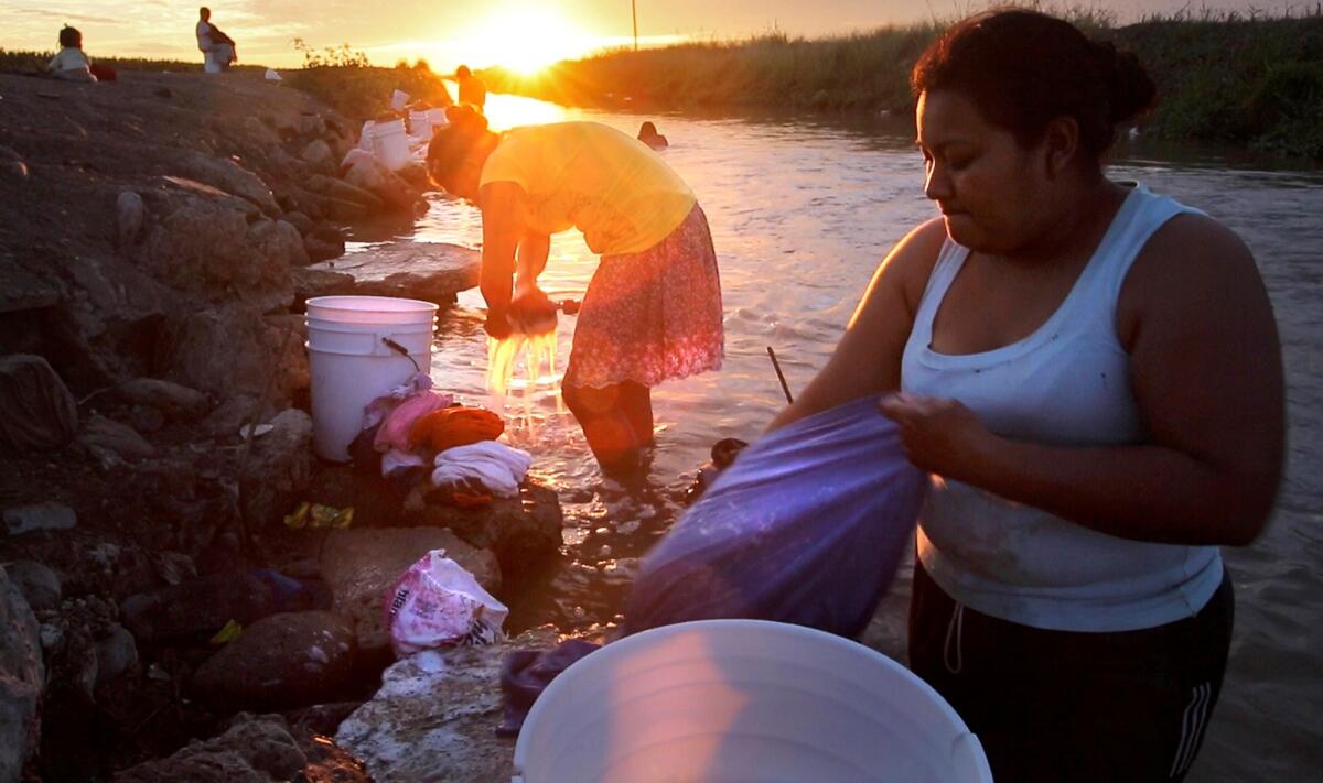 Women scrub their laundry on rubble in an irrigation canal at the Campo Isabelita farm labor camp in Costa Rica in the Mexican state of Sinaloa.