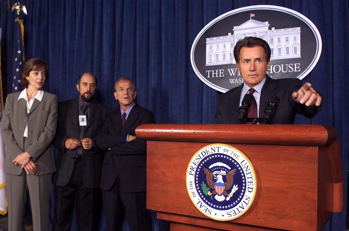 A man points his finger from behind a lectern.