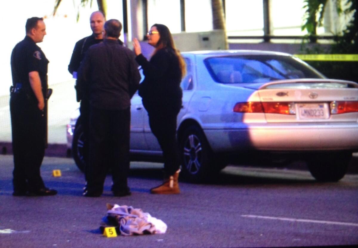 Police talk with people next to a car involved in a pedestrian collision Monday afternoon at Western Avenue and Glenoaks Boulevard. Evidence items with tags are all over the street.