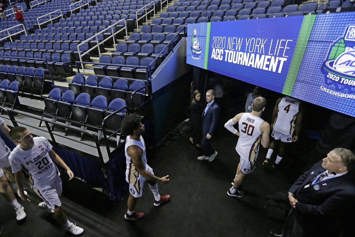 FILE - In this Thursday, March 12, 2020, file photo, Florida State players leave the court after the NCAA college basketball games at the Atlantic Coast Conference tournament in Greensboro, N.C., were cancelled due to the coronavirus. A year after the worldwide coronavirus pandemic stopped all the games in their tracks, the aftershocks are still being felt across every sector. (AP Photo/Gerry Broome, File)