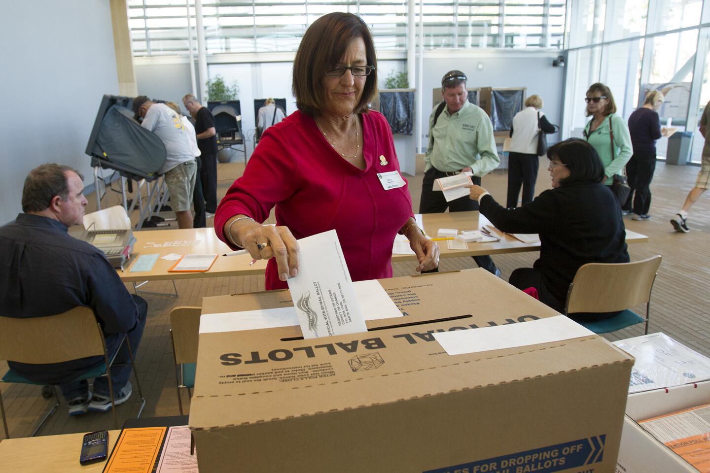 City clerk Betsy Hawkins drops a vote by mail ballot into an official ballot box during a Newport Beach general municipal election and statewide election on Tuesday at Newport Beach Civic Center.