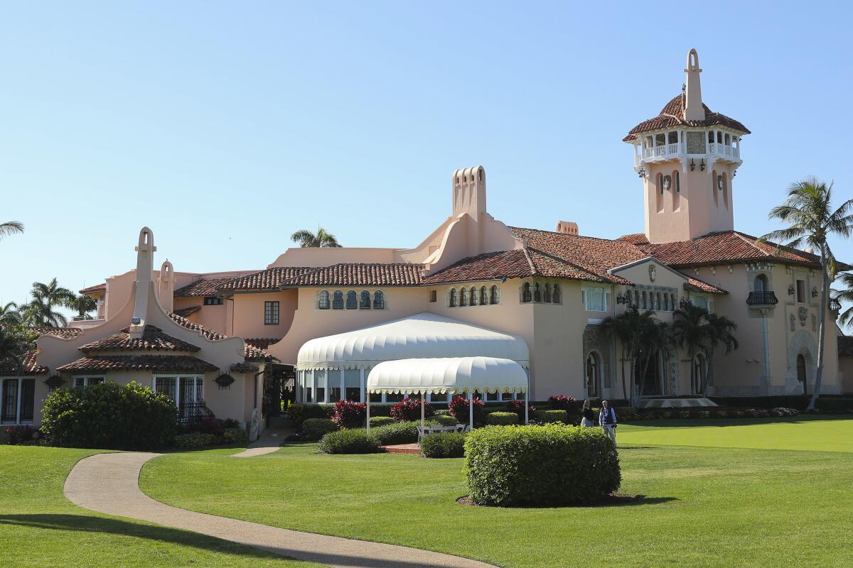 An exterior view of a sprawling, peach-colored Mediterranean-style building with white awnings and green lawns