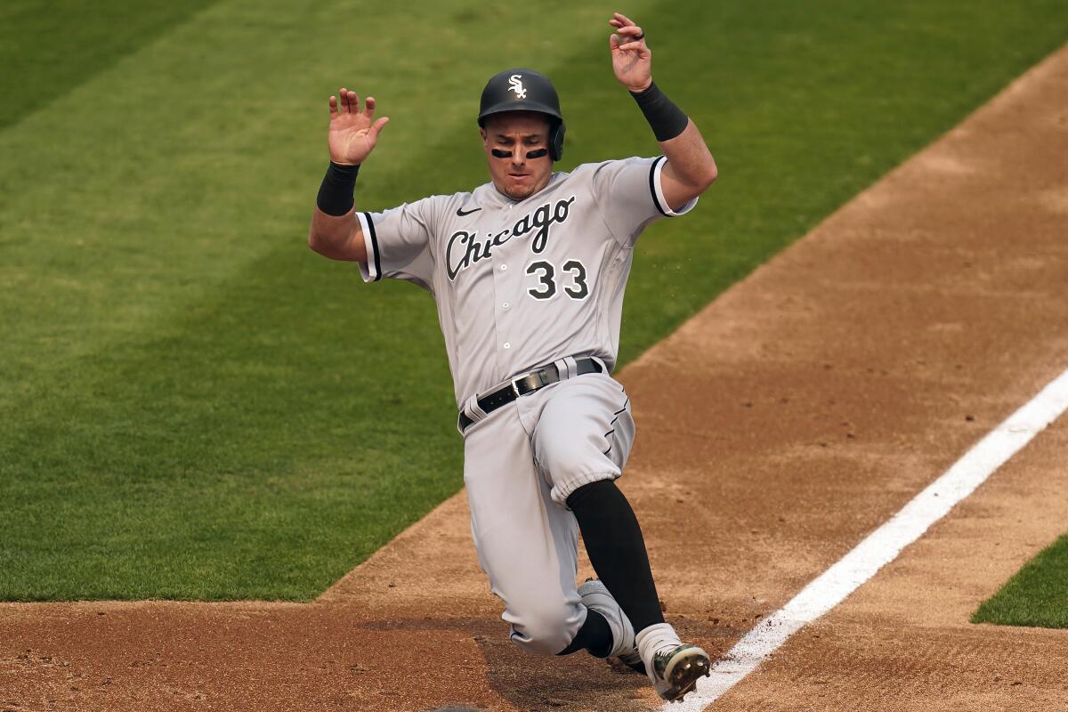 Chicago White Sox catcher James McCann slides into home plate with his hands up.