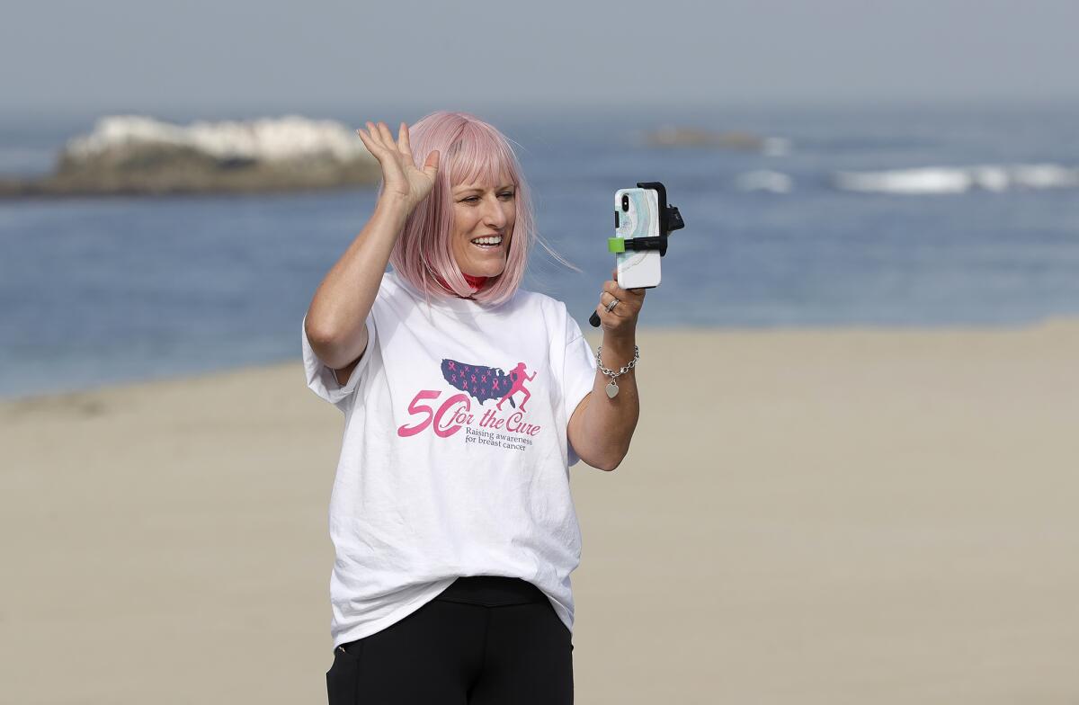 Sharael Kolberg of Laguna Beach, chats with virtual friends during her "50 for the Cure" walk at Main Beach.