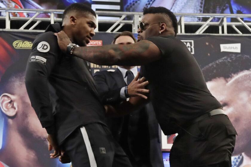 British boxer Anthony Joshua, left, is shoved by Jarrell Miller, right, as they pose for photographs during a news conference Tuesday, Feb. 19, 2019, in New York, to promote their upcoming fight. (AP Photo/Frank Franklin II)