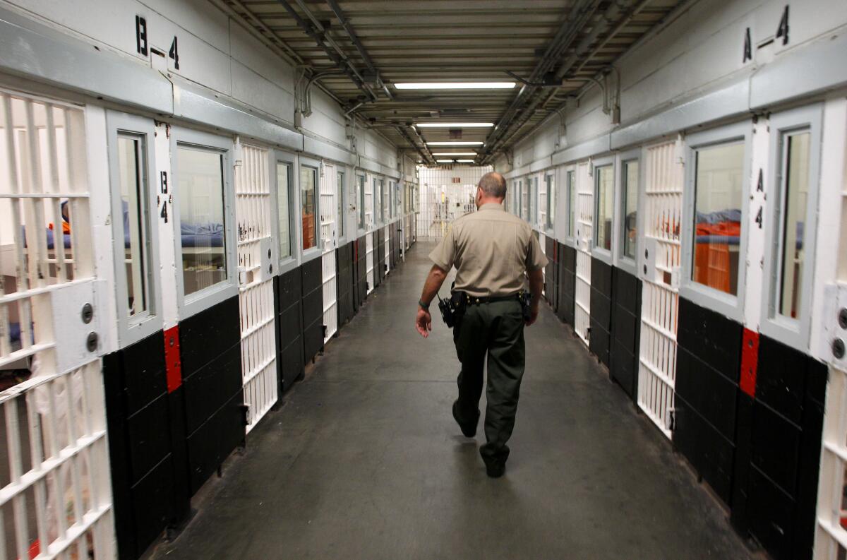A staff member walks down a jail corridor.