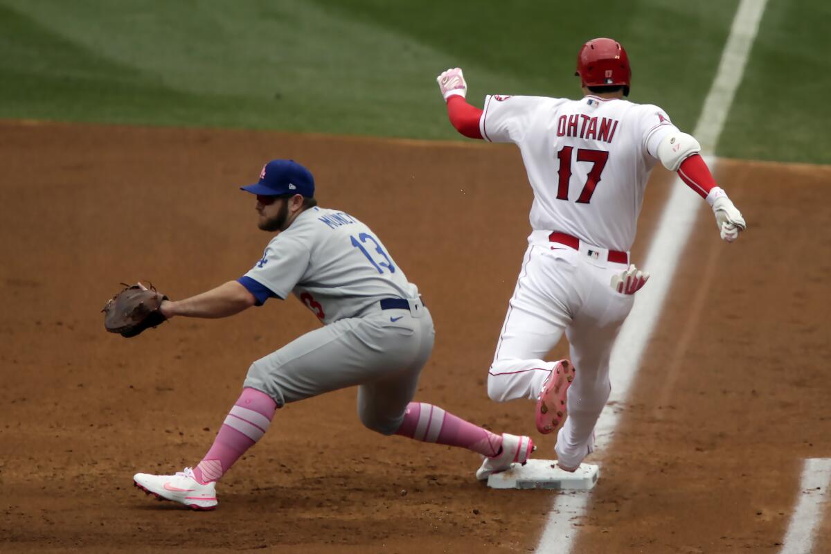Angels designated hitter Shohei Ohtani, right, beats a throw to Dodgers first baseman Max Muncy.