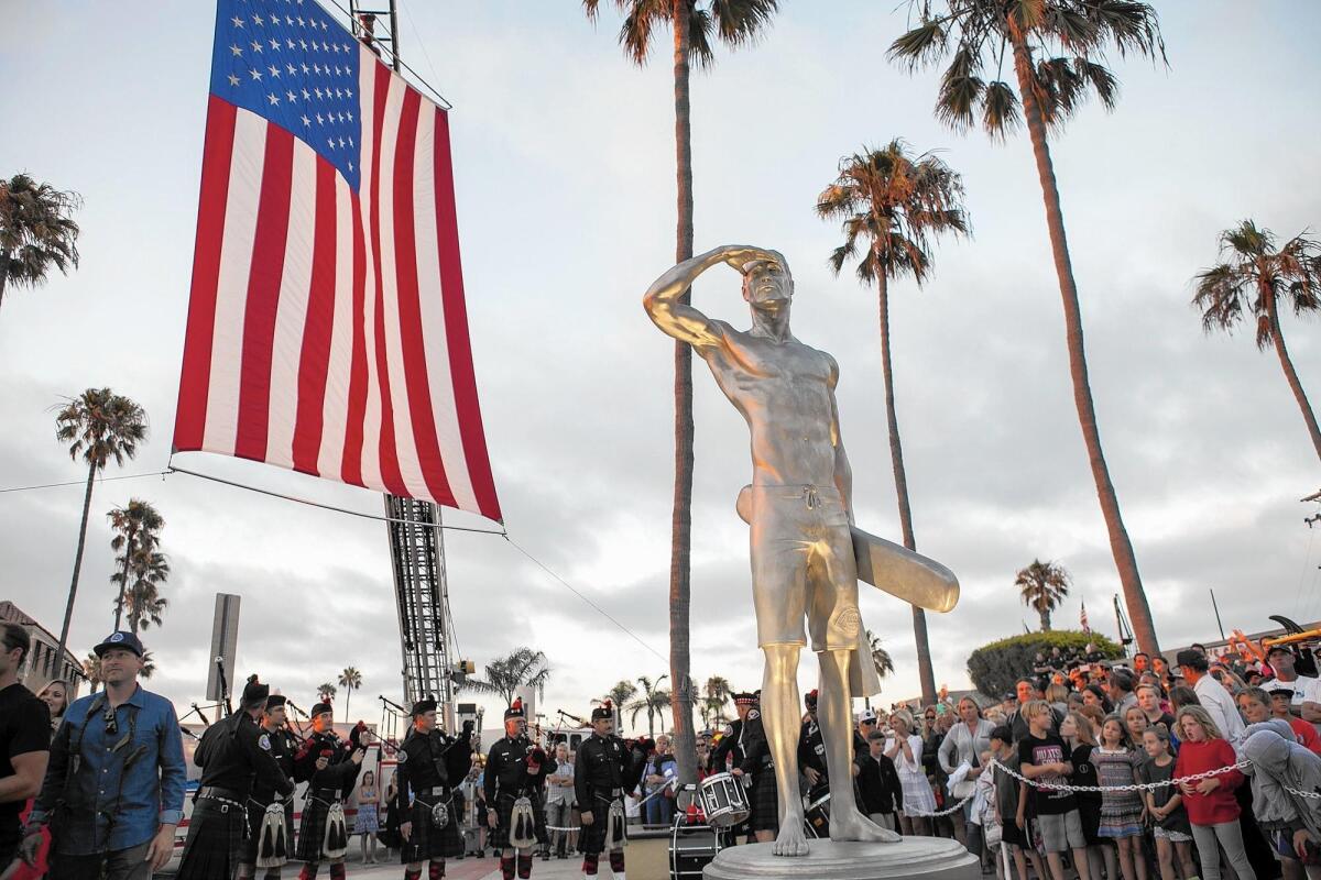 A 9-foot-tall stainless-steel statue of late Newport Beach lifeguard Ben Carlson is unveiled near the Newport Pier. Carlson, 32, died two years ago while rescuing a distressed swimmer.