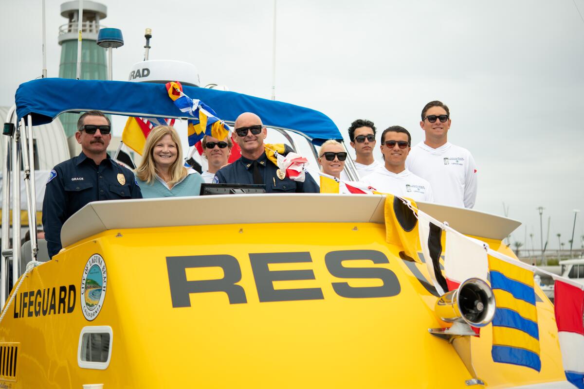 Laguna Beach lifeguard Matt Grace, Mayor Sue Kempf, and Acting Marine Safety Chief Kai Bond pose aboard Wave Watch.