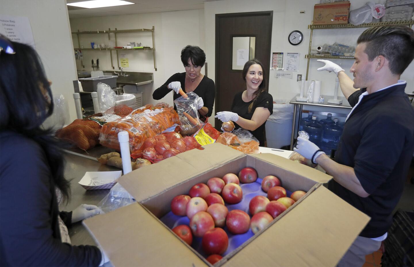 Volunteers Parisa Dehdashti, Denise Fleig, Alejandra Seymour and Brad Morrow, from left, of First Team Real Estate in Newport Beach bag produce to go with Thanksgiving food bags at Share Our Selves in Costa Mesa on Tuesday.