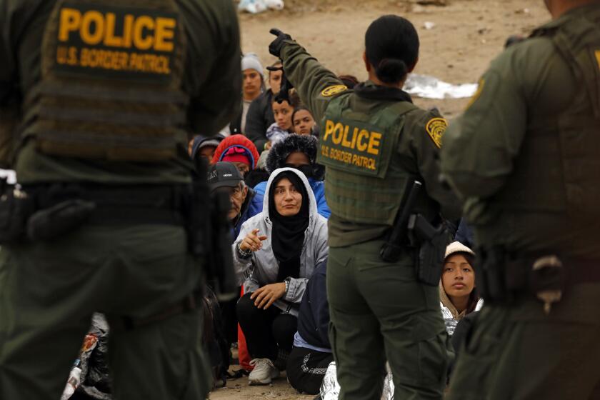 U.S. border, United States-May 11, 2023-U.S. border patrol agents make contact with migrants hoping to cross into the United States from Tijuana, Mexico on May 11, 2023. . Some migrants have been waiting a week in an area south of the second border wall in anticipation of a change in immigration policy, Title 42, which may allow them to apply for asylum. U.S. border patrol agents give out one bottle of water and one granola bar to each person. There are approximately 500 people in this one camp. (Carolyn Cole / Los Angeles Times)