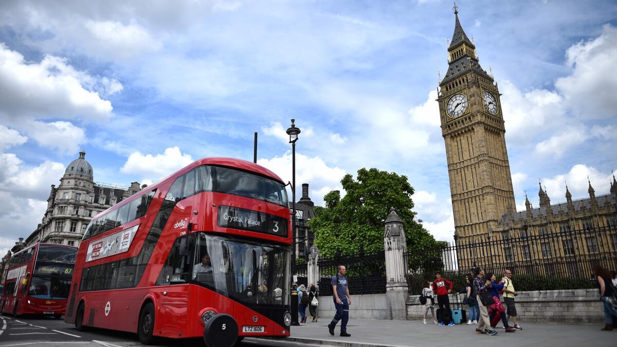 Red buses travel past the Elizabeth Tower, center, which houses the "Big Ben" bell in the Palace of Westminster in central London. Airfares to Britain have dropped since the Brexit vote, a new study found.
