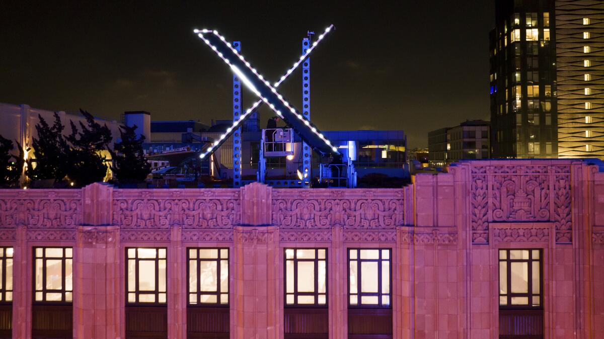 Workers install lighting on an 'X' sign atop the company headquarters in downtown San Francisco.