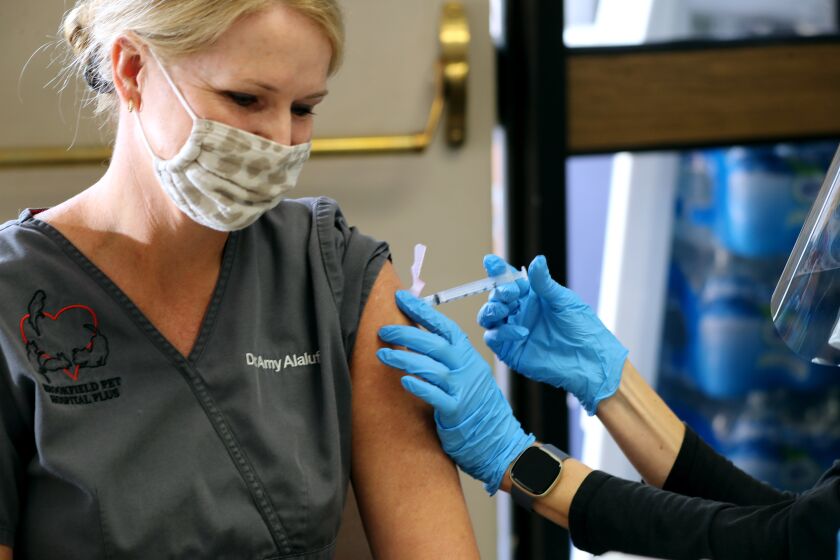 Veterinary doctor Amy Valentine Alaluf gets her Covid-19 vaccine from Karen L. Simerlink, R.N., at the Central Net Training Center in Huntington Beach on Wednesday, Jan. 13, 2021. The vaccine is available by appointment to tier 1A individuals.