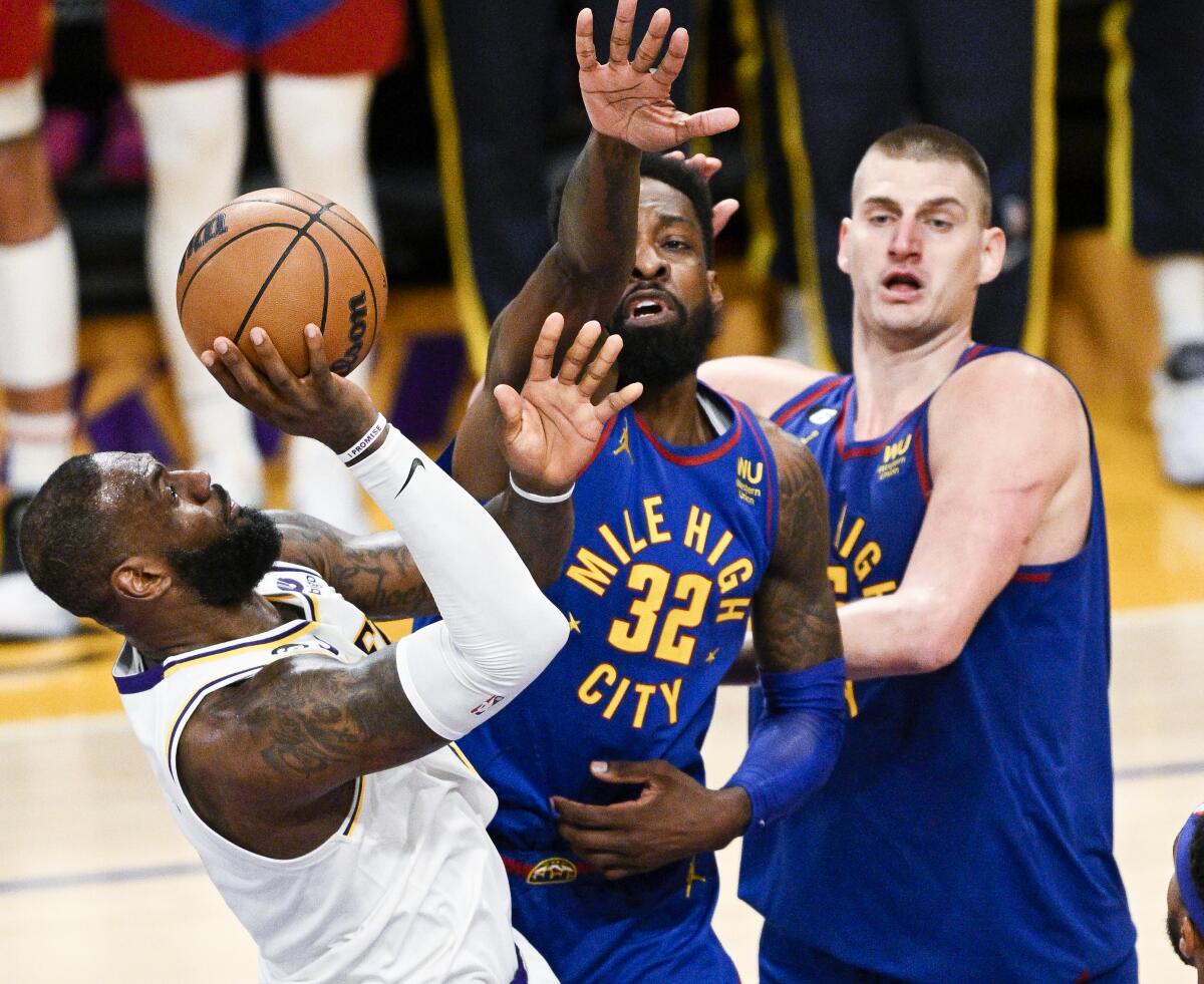 Lakers forward LeBron James, left, attempts a fadeway shot while he's fouled by Nuggets forward Jeff Green.