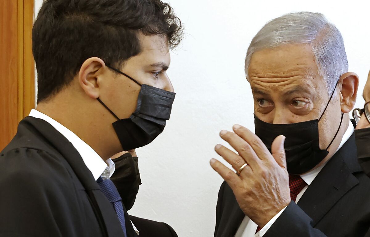Former Israeli prime minister Benjamin Netanyahu, right, arrives for a court hearing on corruption charges Tuesday, Nov. 16, 2021, in Jerusalem. Netanyahu appeared in court for the first time in over half a year on Tuesday as a one-time confidant prepared to take the stand against him in a high-profile corruption case against the former Israeli prime minister. (Jack Guez/Pool Photo via AP)