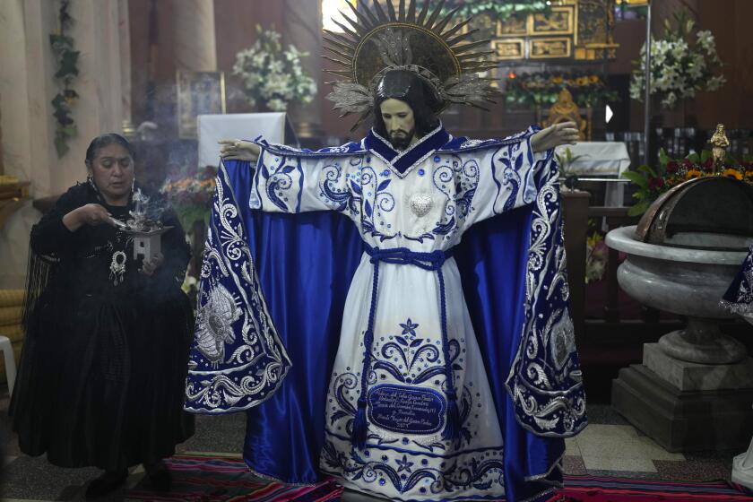 Una devota quema incienso después de vestir una estatua del Señor Jesús del Gran Poder dentro de la iglesia católica del mismo nombre, en preparación para el próximo festival anual, en La Paz, Bolivia, el jueves 23 de mayo de 2024. (Foto AP/Juan Karita)