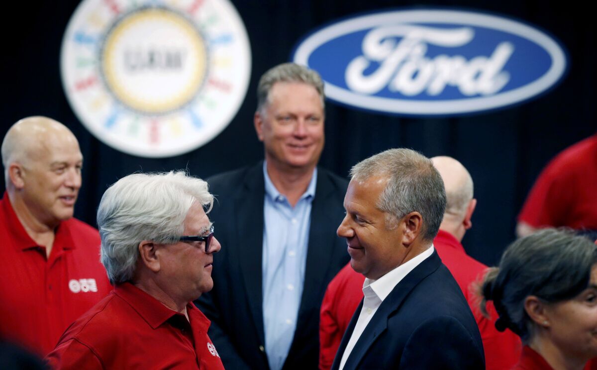 FILE - In this Monday, July 15, 2019, file photo, United Auto Workers Local 600 President Bernie Ricke, left, talks with Ford Motor Co., President Automotive Joseph R. Hinrichs after opening contract talks in Dearborn, Mich. The United Auto Workers union said late Wednesday, Oct. 30 that it has reached a tentative contract agreement with Ford after three days of intense bargaining. (AP Photo/Carlos Osorio, File)