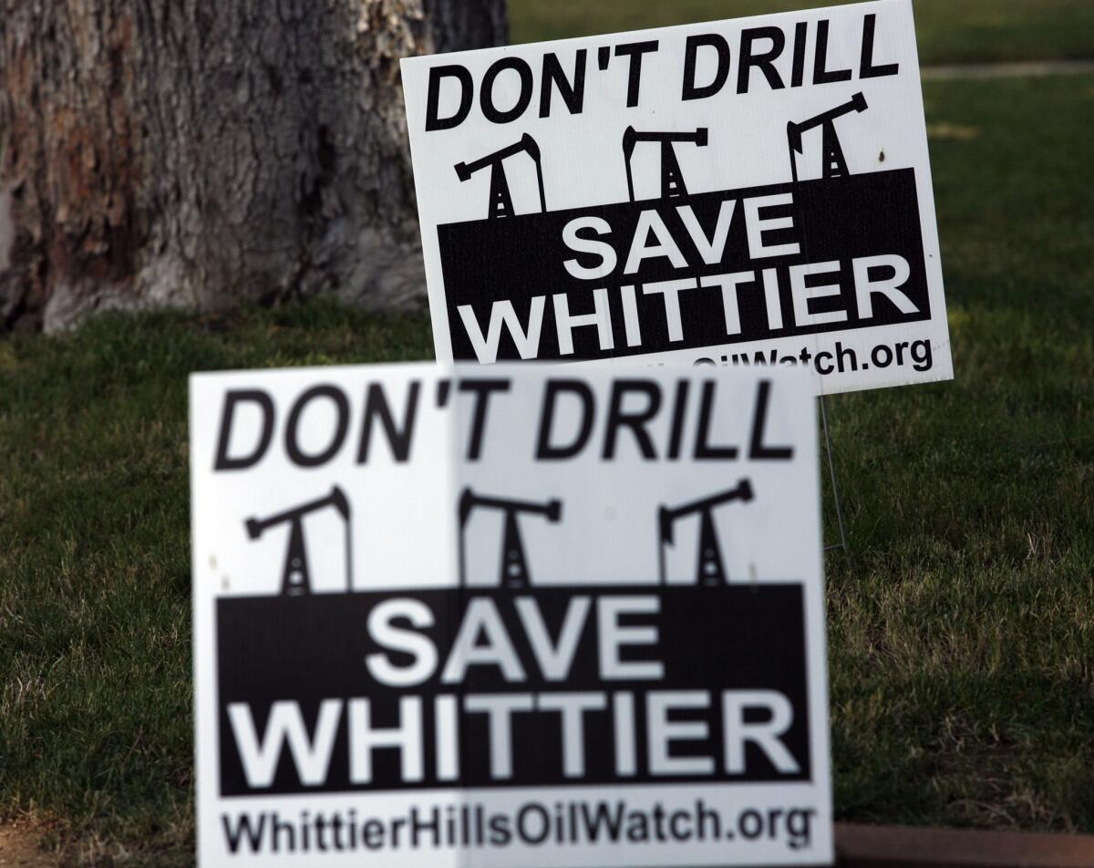 Signs in a Whittier resident's yard show opposition to oil drilling in the city.