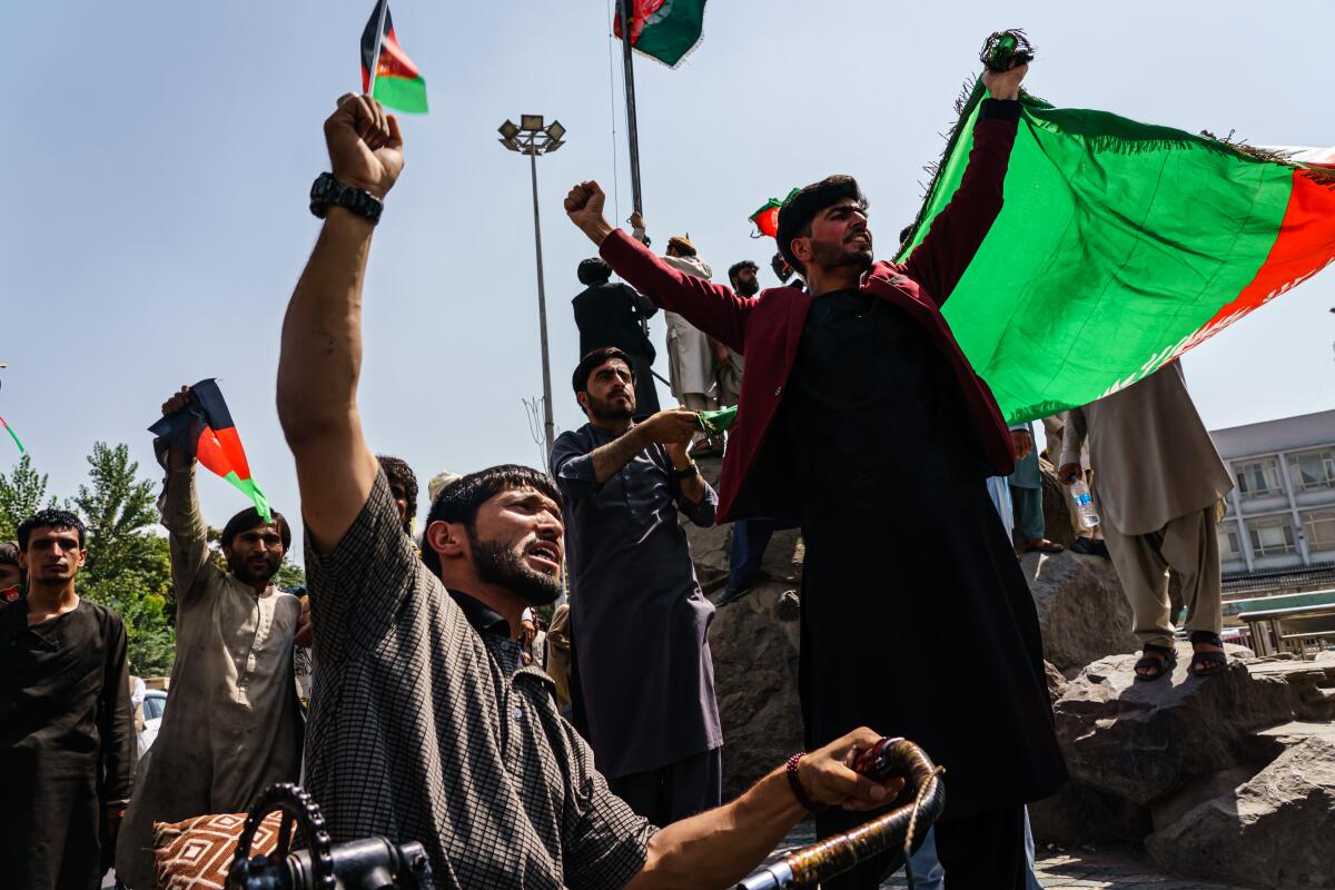 Afghans try to raise the national flag of Afghanistan at Pashtunistan Square in Kabul