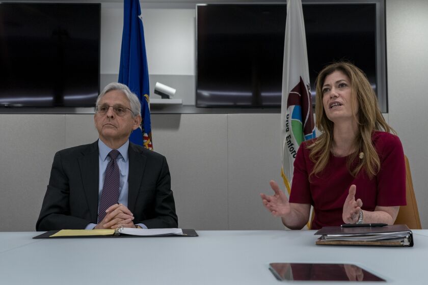 Attorney General Merrick Garland, left, listens as Drug Enforcement Administration Administrator Anne Milgram, right, speaks during in a press event to announce the results of an enforcement surge to reduce the fentanyl supply across the United States, at DEA headquarters, Arlington, Va., Tuesday, Sept. 27, 2022. (AP Photo/Gemunu Amarasinghe)