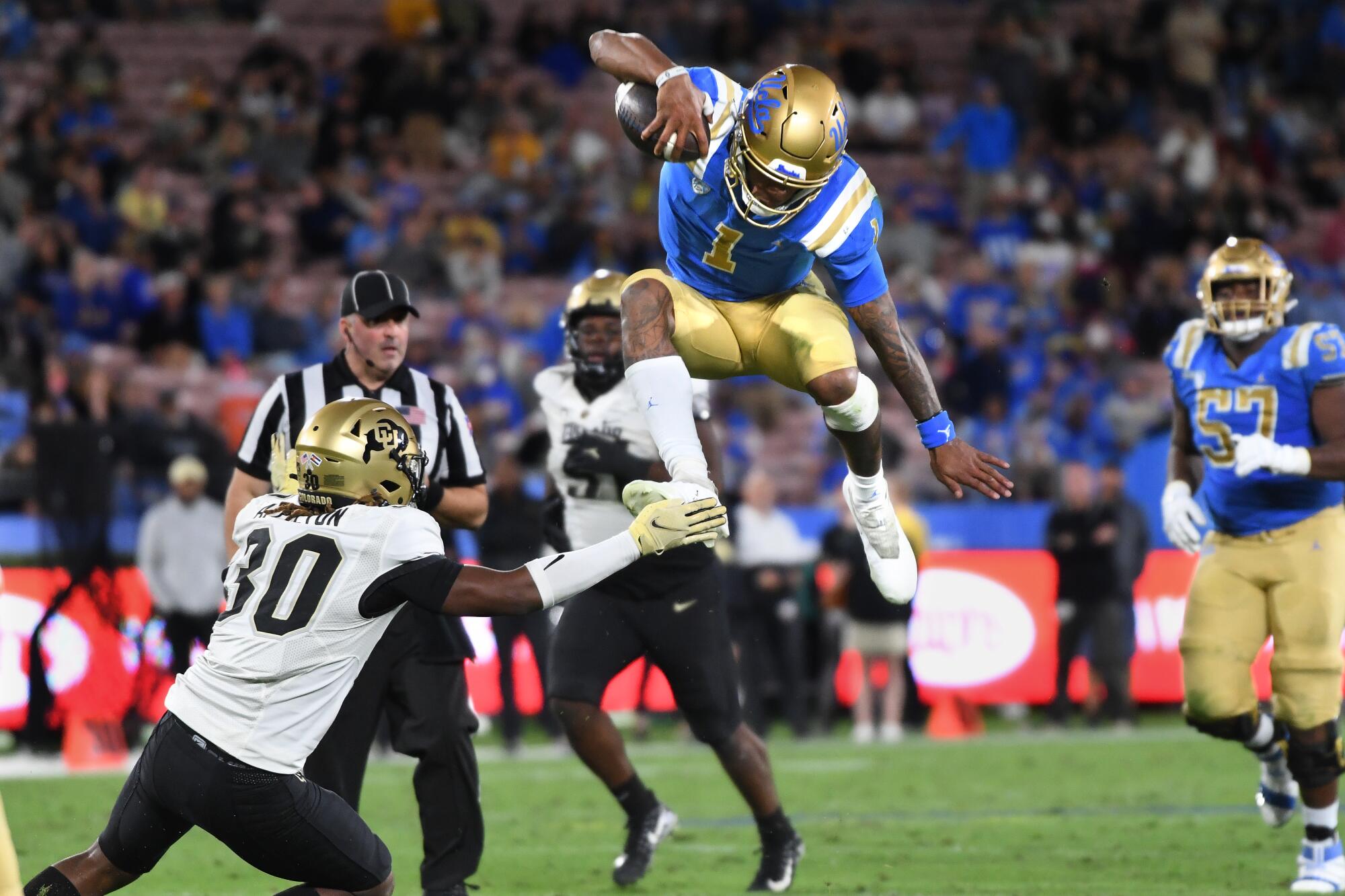UCLA quarterback Dorian Thompson-Robinson leaps over Colorado safety Curtis Appleton.