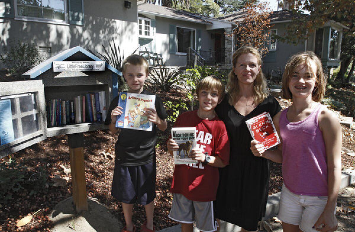 Nicole Berklas, second from right, and her children Gage, left, August, second from left, and Laura, right, in front of their home on the 800 block of West Mountain Ave., where a Little Free Library kiosk contains books, in Glendale on Saturday, September 14, 2013. People can take books, borrow books and leave books for others in the kiosk.