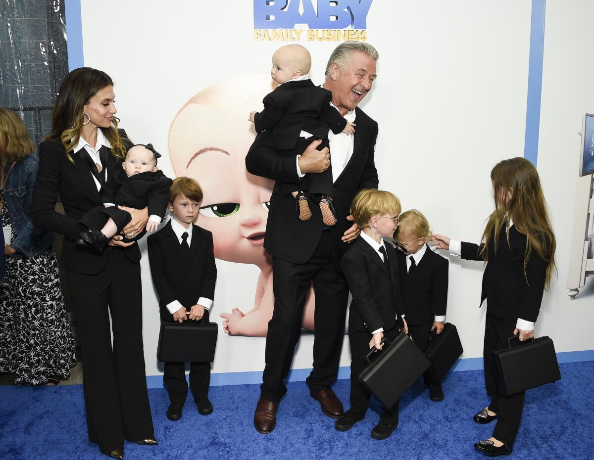 A mother and father wrangle six kids who are all wearing black suits and ties at a premiere.