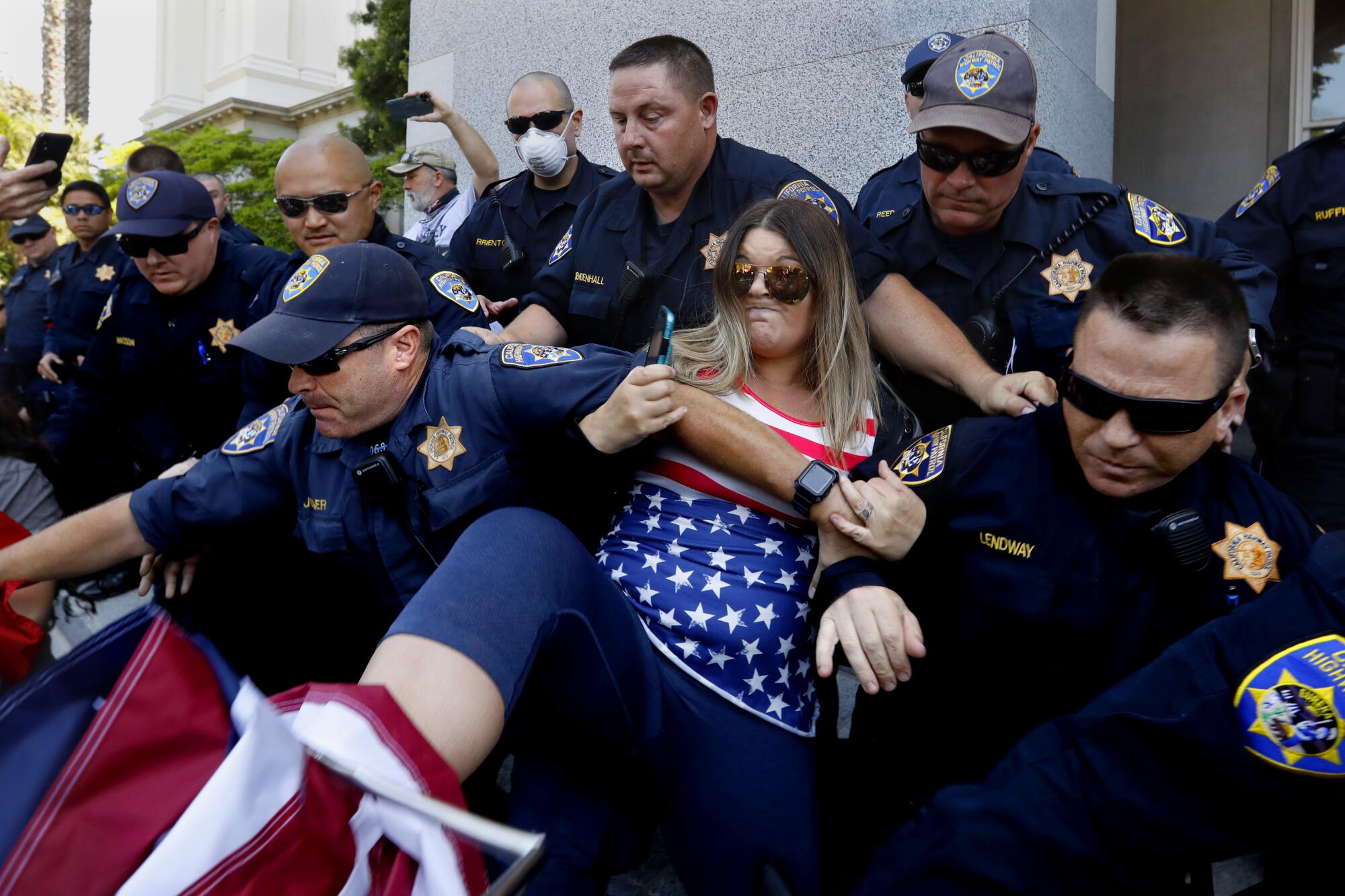 California Highway Patrol officers take into custody a woman who refused to follow orders to move off the Capitol grounds during a protest Friday
