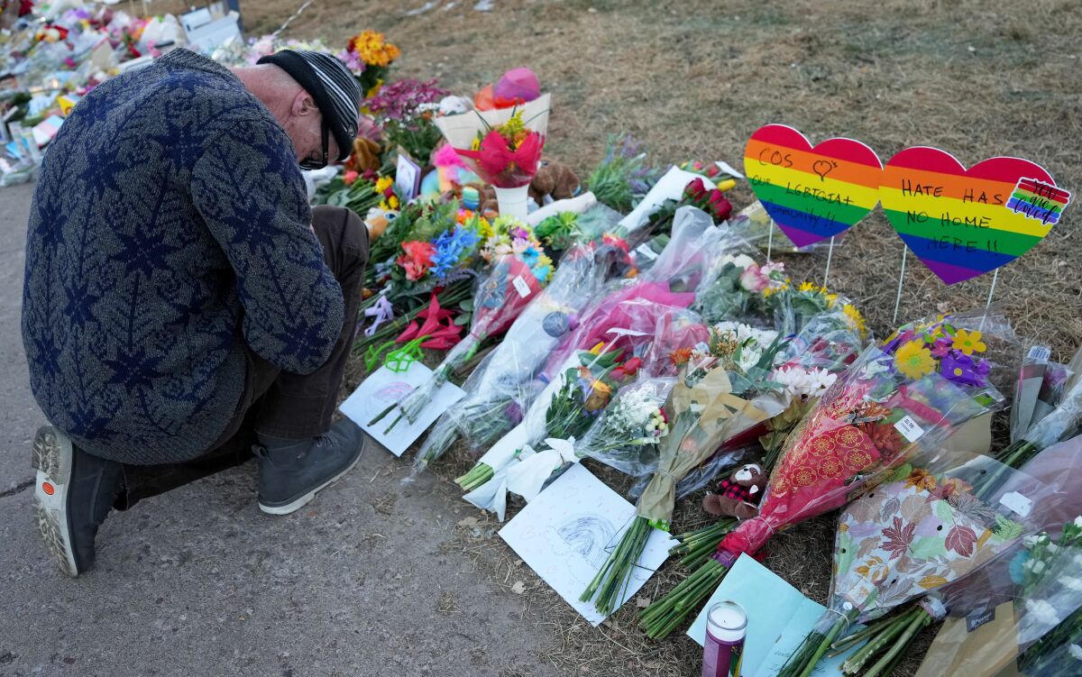 Un uomo si inginocchia davanti a un memoriale improvvisato con dei fiori