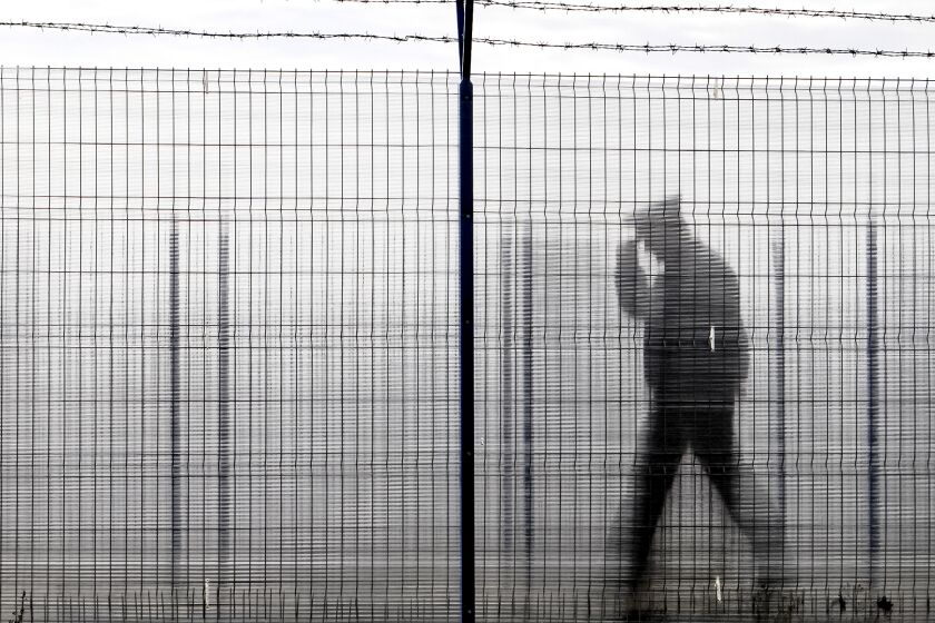 FILE - A Romanian border police officer, seen through a plexiglass fence, patrols a railway border crossing point between Romania and Moldova in Ungheni, Romania, on Jan. 18, 2011. European Union countries will weigh on Thursday, Dec. 8, 2022, whether the bloc's three newest members — Bulgaria, Romania, and Croatia — can fully open their borders and participate in Europe's ID check-free travel zone, but more delays to their entry appear likely. (AP Photo/Vadim Ghirda, File)