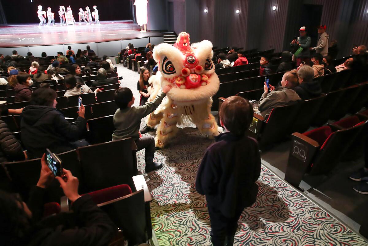 A lion as part of the Gio Nam Lion Dance team, greets a youngster in the aisle.
