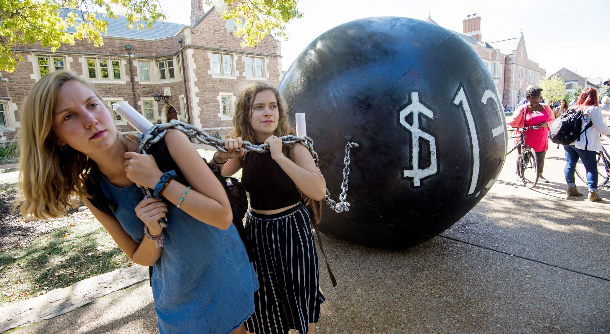 Protesters drag a giant ball and chain representing student debt.
