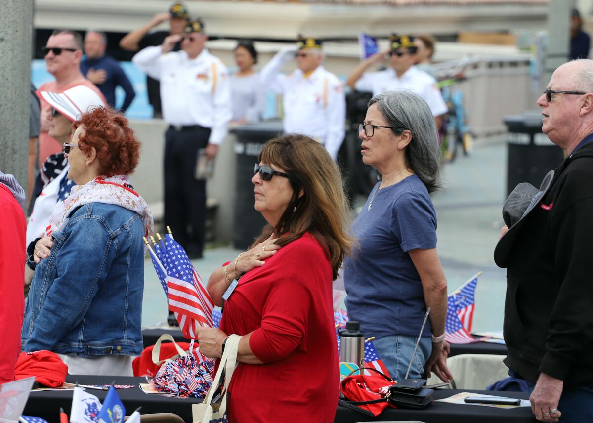 Guests place their hands over their hearts for the Pledge of Allegiance on Sunday in Huntington Beach. 