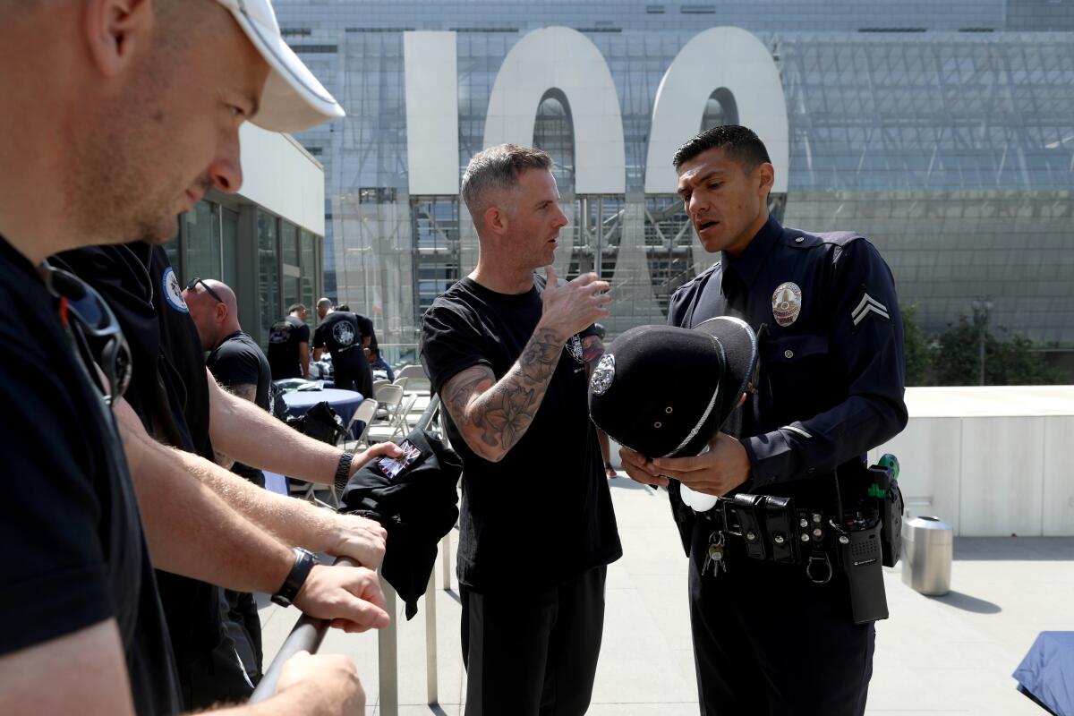 Police Constable Matthew Goodwin gives LAPD Officer Gabriel Flores a police helmet.