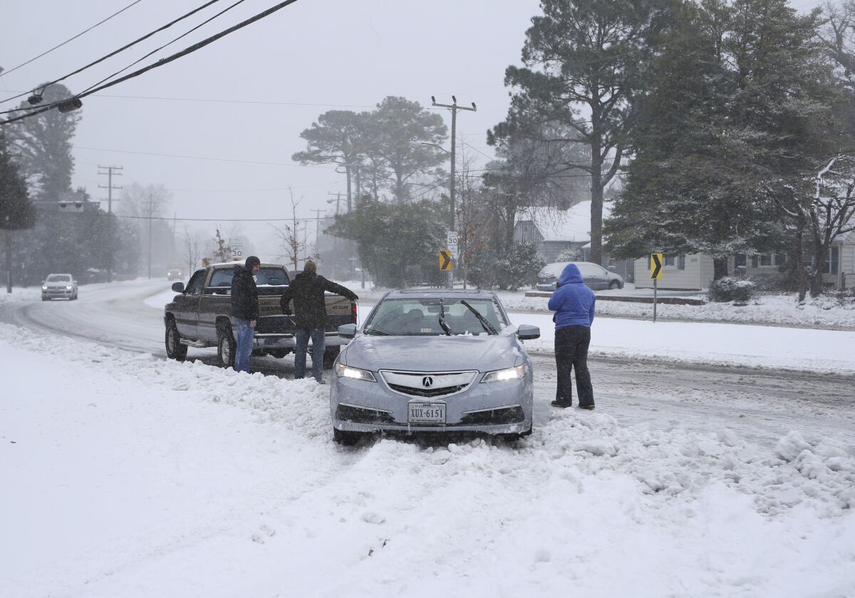 FILE - Good samaritans help pull a woman's car out of the snow during snowstorm Saturday, Jan. 7, 2016 in Norfolk, Va. Taking a few simple steps ahead of winter weather can make driving in the cold a safer experience.(AP Photo/Jason Hirschfeld, File)
