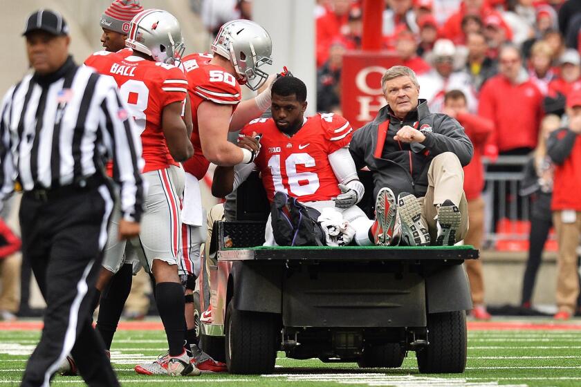 Ohio State quarterback J.T. Barrett is comforted by teammate Jacoby Boren while being carted off the field after injuring his leg during the fourth quarter against Michigan at Ohio Stadium on Saturday.