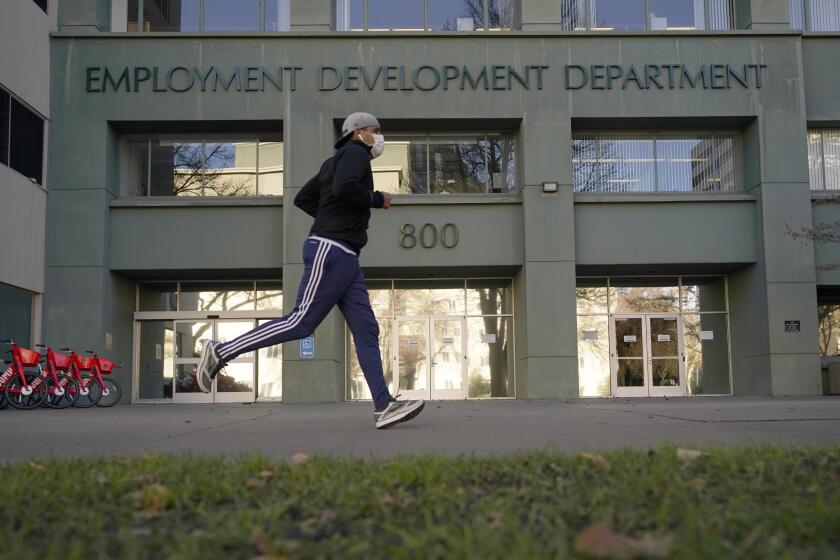 FILE - In this Dec. 18, 2020, file photo a runner passes the office of the California Employment Development Department in Sacramento, Calif. California employers added more than 100,000 jobs in May for the fourth month in a row. Numbers from the Employment Development Department released Friday, June 18, 2021, show California has now regained 51% of the 2.7 million jobs it lost at the start of the pandemic. (AP Photo/Rich Pedroncelli, File)