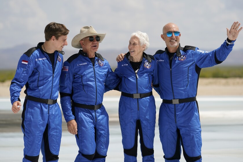 Oliver Daemen, from left, Jeff Bezos, founder of Amazon and space tourism company Blue Origin, Wally Funk and Bezos' brother Mark pose for photos in front of the Blue Origin New Shepard rocket, derby, after their launch from the spaceport near Van Horn, Texas, Tuesday, July 20, 2021. (AP Photo/Tony Gutierrez)