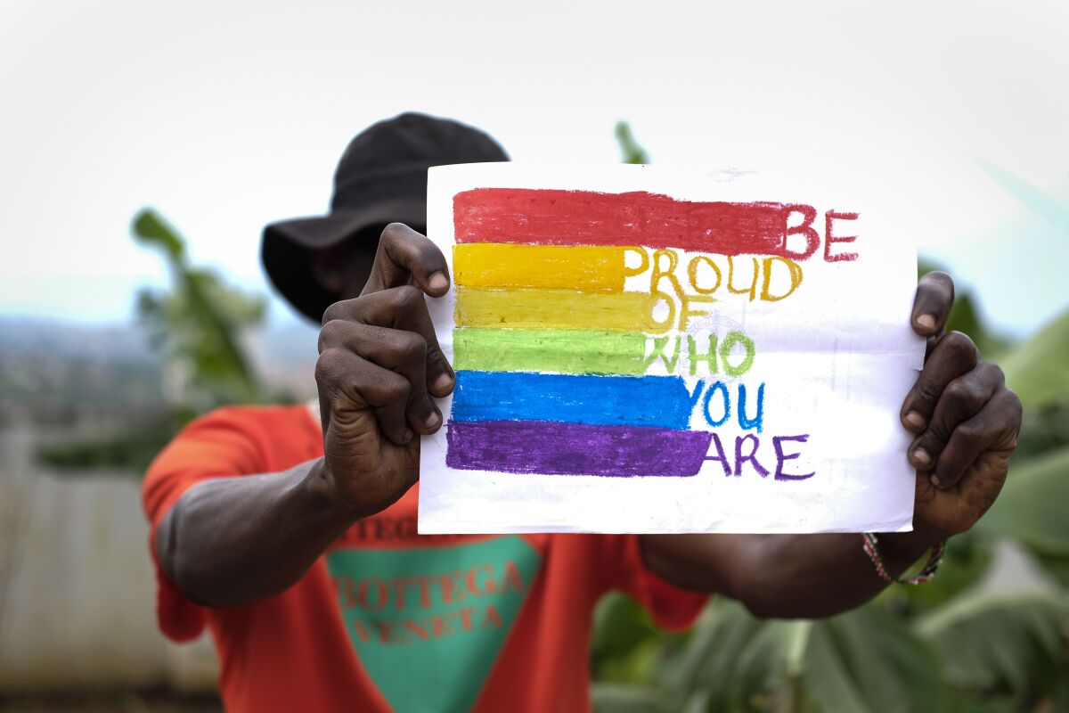 A gay Ugandan man holds a pride sign as he poses for a photograph in Uganda Saturday, March 25, 2023. A prominent leader of Uganda's LGBTQ community on Thursday described anguished calls by others like him who are concerned for their safety after the passing of a harsh new anti-gay bill. (AP Photo)