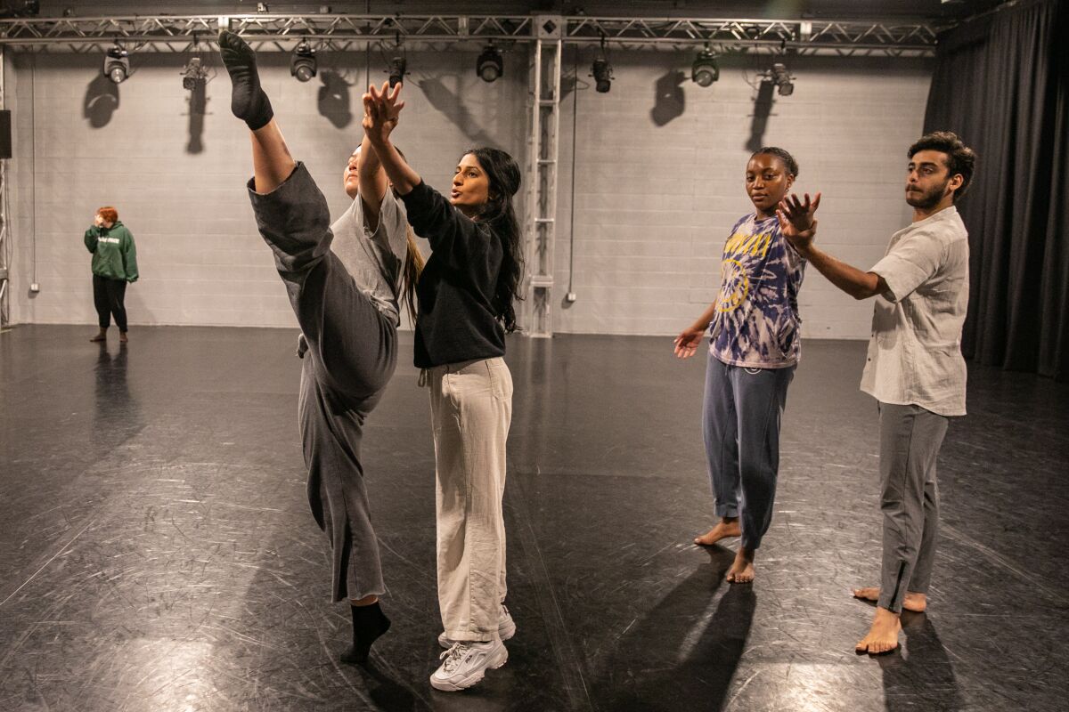 Two choreographers holding the hands of two dancers to teach material.