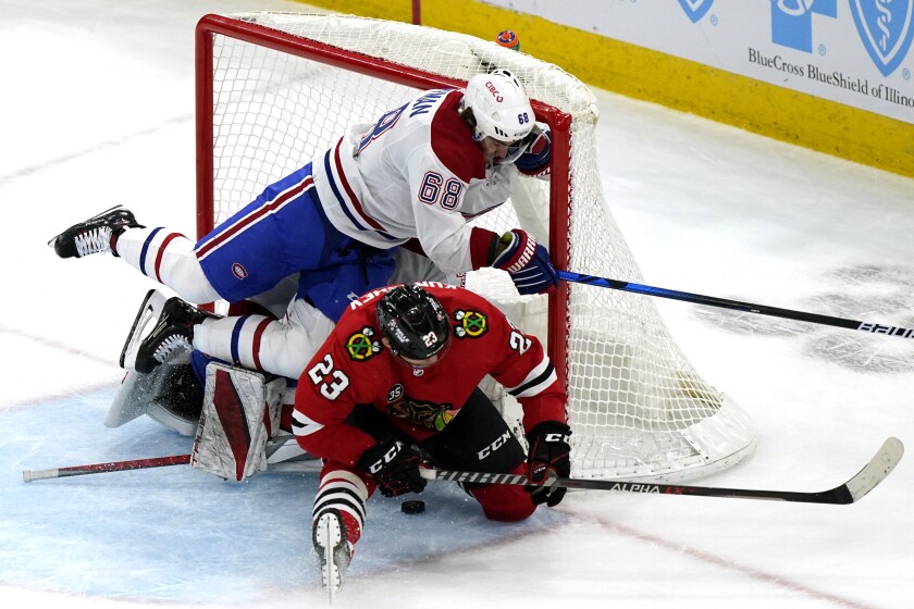 Chicago Blackhawks center Philipp Kurashev (23) scores the game-winning goal against Montreal Canadiens center Mike Hoffman (68) and goaltender Sam Montembeault during overtime period of an NHL hockey game in Chicago, Thursday, Jan. 13, 2022. The Chicago Blackhawks won 3-2 in overtime. (AP Photo/Nam Y. Huh)