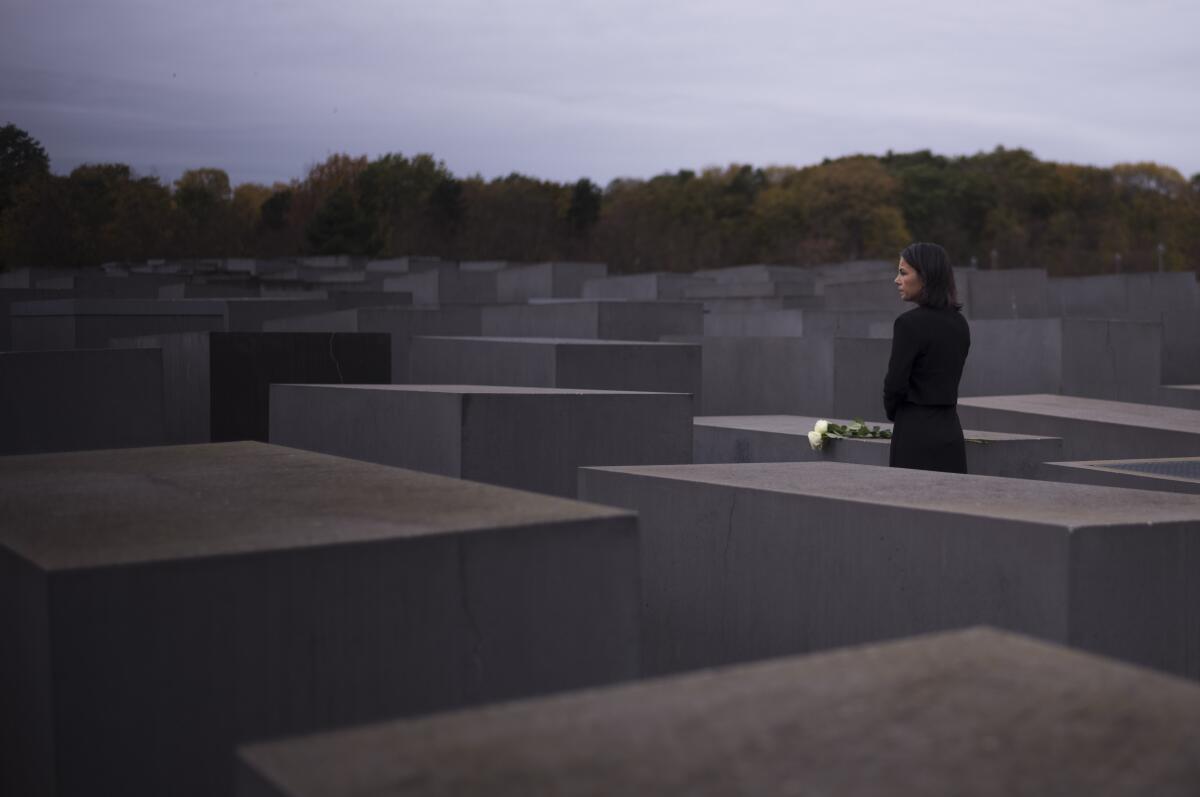 A woman places flowers at a memorial made up of large concrete blocks 