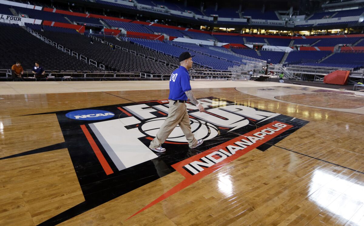 A worker crosses the NCAA Final Four center court logo in Indianapolis where there is growing pressure on the NCAA to take a stand against controversial Indiana law.