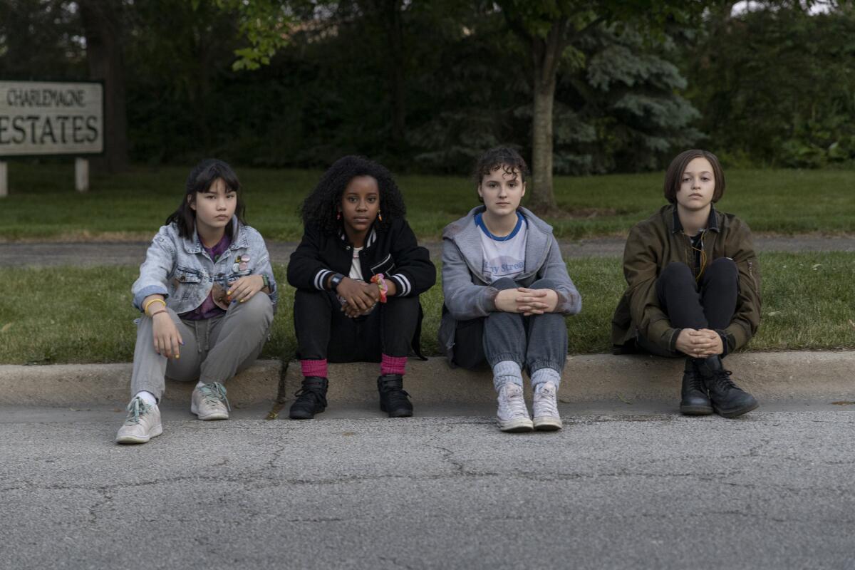 Four 12-year-old girls sitting on a curb on a suburban street