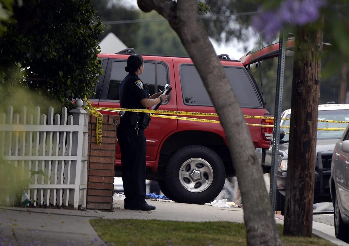 A policewoman inspects the car of a victim of the killer that went on a shooting spree in Santa Monica on Friday.