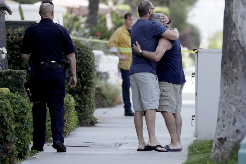 Family members console one another outside a Redondo Beach condo complex, where three people were found dead in the 700 block of the Esplanade.