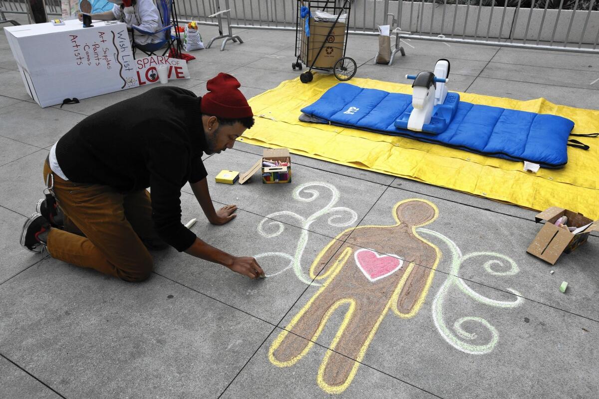 A man who gave his full name as Foremost draws on the sidewalk before protesters loosely tied to the national "Black Lives Matter" campaign hold a news conference outside LAPD headquarters.